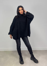 Pull oversize noir — vue portée en pied, col roulé et jean noir ajusté, bottes épaisses