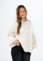 Cardigan oversize beige clair — vue portée de trois-quarts, regard détourné, volume des manches