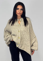 Cardigan oversize beige — vue portée de face en intérieur, devant un mur blanc