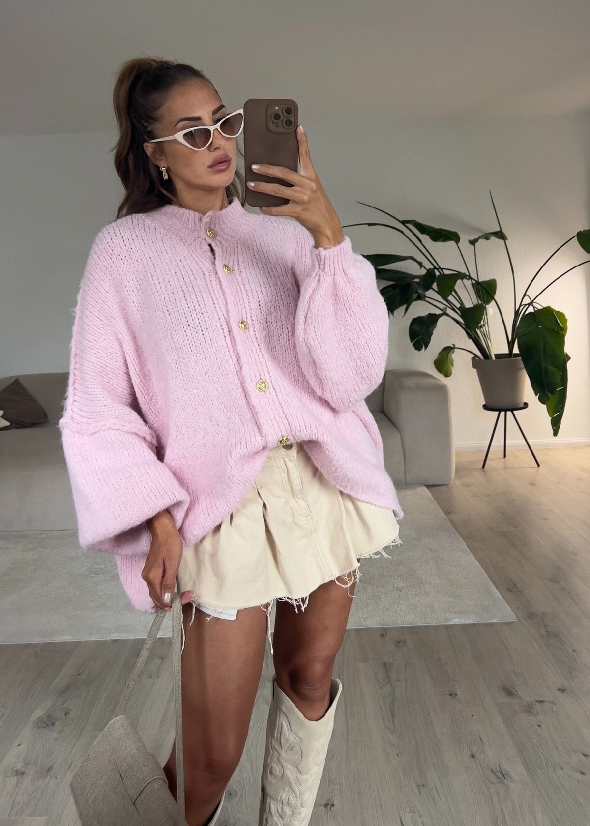 Cardigan oversize rose — selfie au miroir, vue portée en pied, jupe courte beige à volants et bottes blanches