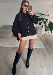 Cardigan oversize brun foncé — vue portée en pied, mini-jupe claire et pochette blanche