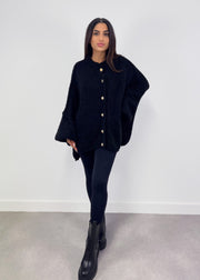 Cardigan oversize noir — vue portée en pied, manches très larges, legging noir et bottes