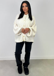 Cardigan oversize beige clair — vue portée en pied, pantalon noir et bottes, fond blanc