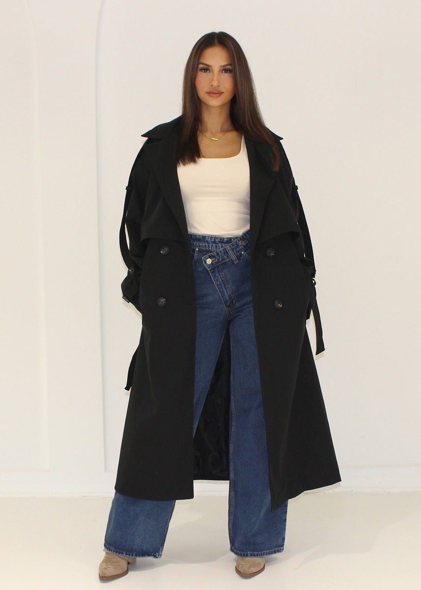 Trench oversize noir — vue portée en pied, ouvert sur un haut blanc et jean large