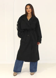 Trench oversize noir — vue portée en pied, ceinturé à la taille