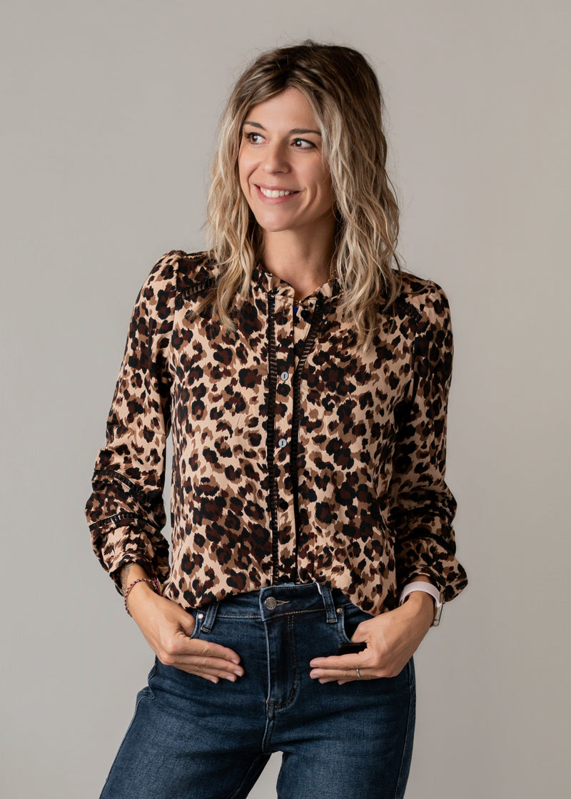 Blouse fluide léopard ajourée portée par une femme, vue rapprochée, jean foncé, mains dans les poches
