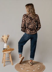 Jean en denim coupe arrondie porté par une femme, vue de dos, blouse léopard