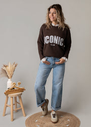 Pull en maille dentelle brodée porté par une femme, silhouette entière, jean large, tabouret