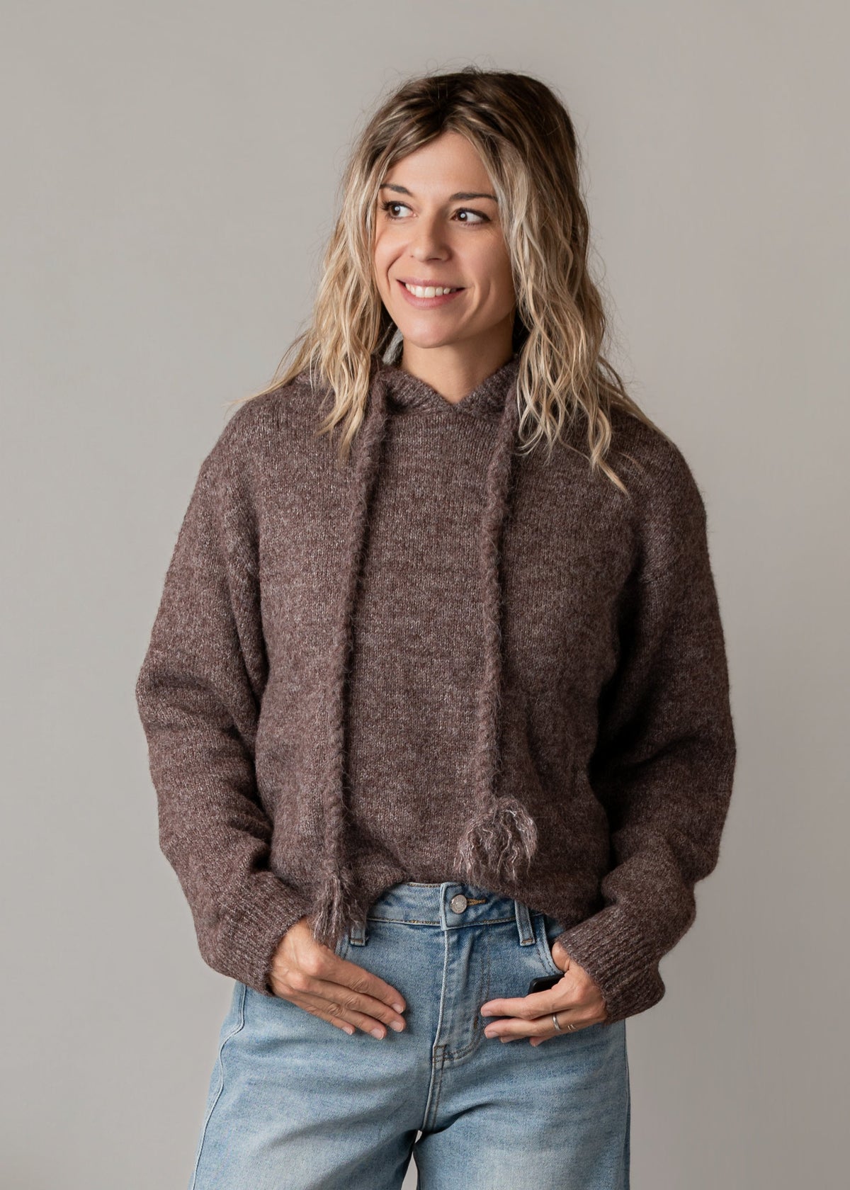 Sweat à capuche à pompons porté par une femme, vue rapprochée, pompons, mains dans les poches