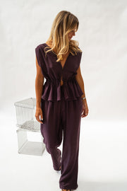 Pantalon fluide en tissu léger porté par une femme, silhouette entière, fond blanc, haut aubergine sans manches