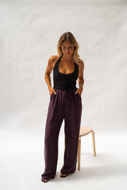 Pantalon fluide en tissu léger porté par une femme, silhouette entière, haut noir, tabouret