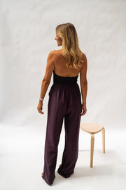 Pantalon fluide en tissu léger porté par une femme, vue de dos, haut noir, tabouret