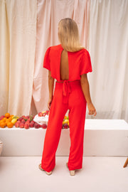 Pantalon fluide à fermeture latérale porté par une femme, vue de dos, cheveux attachés, pantalon rouge