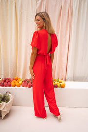 Pantalon fluide à fermeture latérale porté par une femme, vue de dos, rideau, fruits