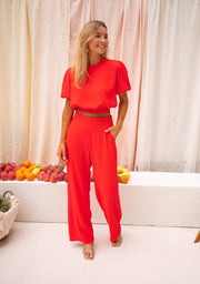 Pantalon fluide à fermeture latérale porté par une femme, vue de face, mains sur la taille