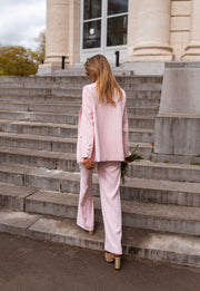 Pantalon droit fluide porté par une femme, vue de profil, marches, blazer rose