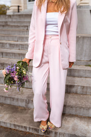 Pantalon droit fluide porté par une femme, silhouette entière, blazer rose, bouquet