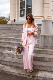 Pantalon droit fluide porté par une femme, silhouette entière, marches, bouquet
