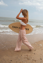 Pantalon fluide rayé à nouer porté par une femme, vue de dos, planche, plage