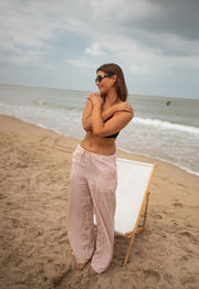 Pantalon fluide rayé à nouer porté par une femme, vue de face, sable, bras croisés