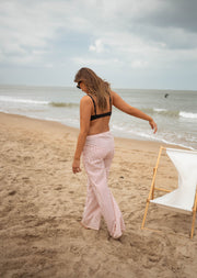 Pantalon fluide rayé à nouer porté par une femme, vue de dos, plage, chaise longue