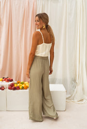 Pantalon fluide taille élastique porté par une femme, vue de dos, rideaux, pantalon large