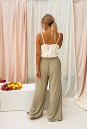 Pantalon fluide taille élastique porté par une femme, vue de dos, rideaux, fruits