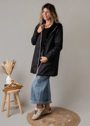Parka réversible à fourrure portée par une femme, silhouette entière, jean évasé, tabouret