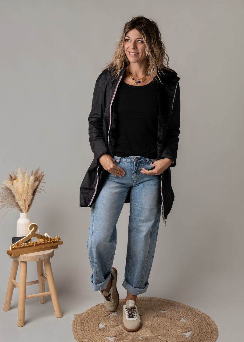 Parka réversible à fourrure portée par une femme, silhouette entière, parka noire, tabouret