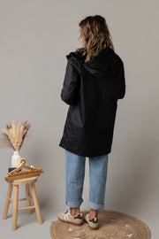 Parka réversible à fourrure portée par une femme, vue de dos, capuche, tabouret