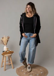 Parka réversible à fourrure portée par une femme, silhouette entière, parka ouverte, tabouret