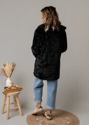 Parka réversible à fourrure portée par une femme, silhouette entière, côté fourrure, tabouret