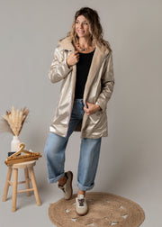 Parka réversible fourrure portée par une femme, silhouette entière, côté doré, tabouret en bois