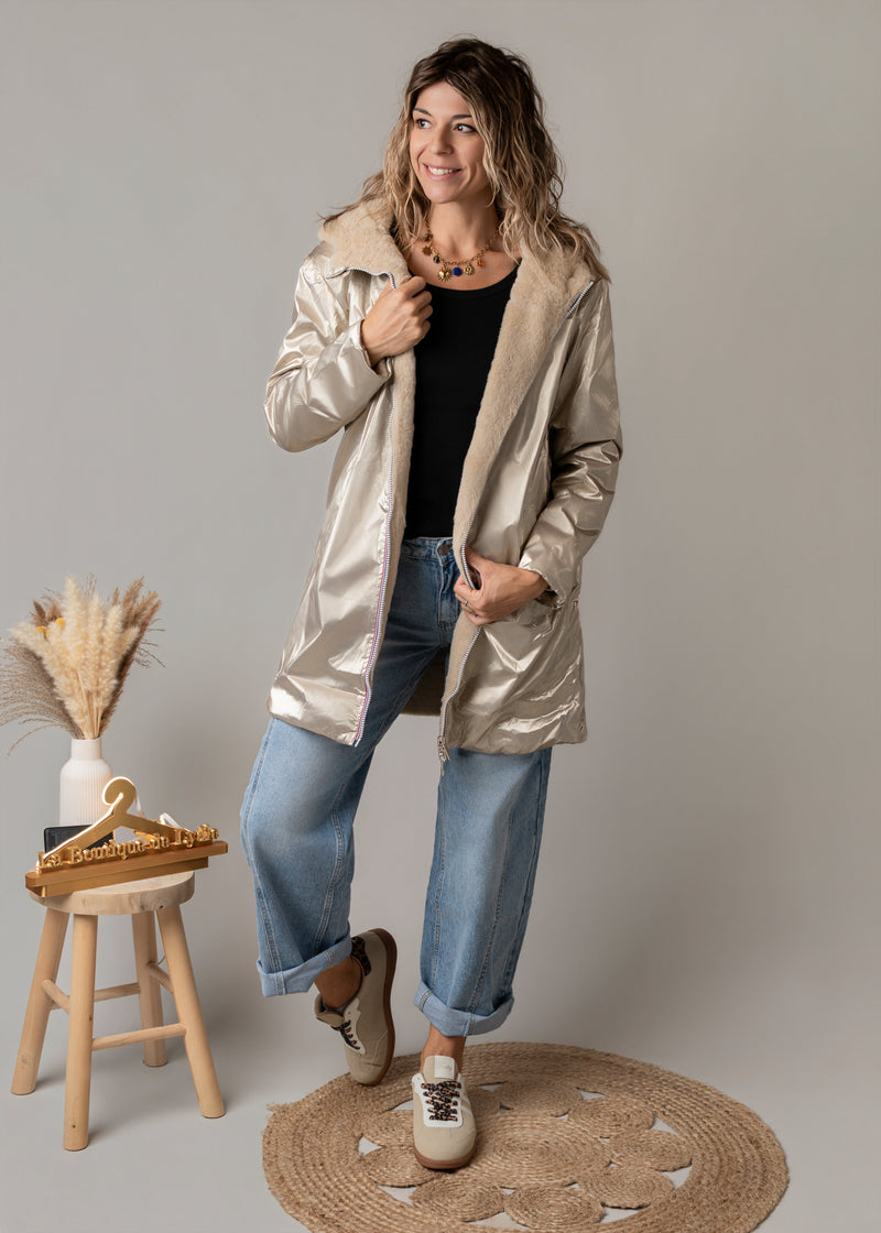 Parka réversible fourrure portée par une femme, silhouette entière, côté doré, tabouret en bois