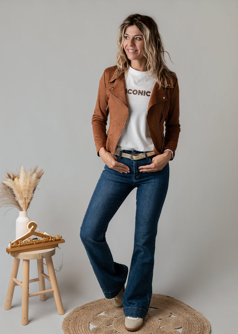 Perfecto en suédine porté par une femme, silhouette entière, jean flare, tabouret