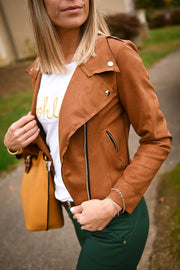 Perfecto en suédine porté par une femme, silhouette entière, sac camel, jardin