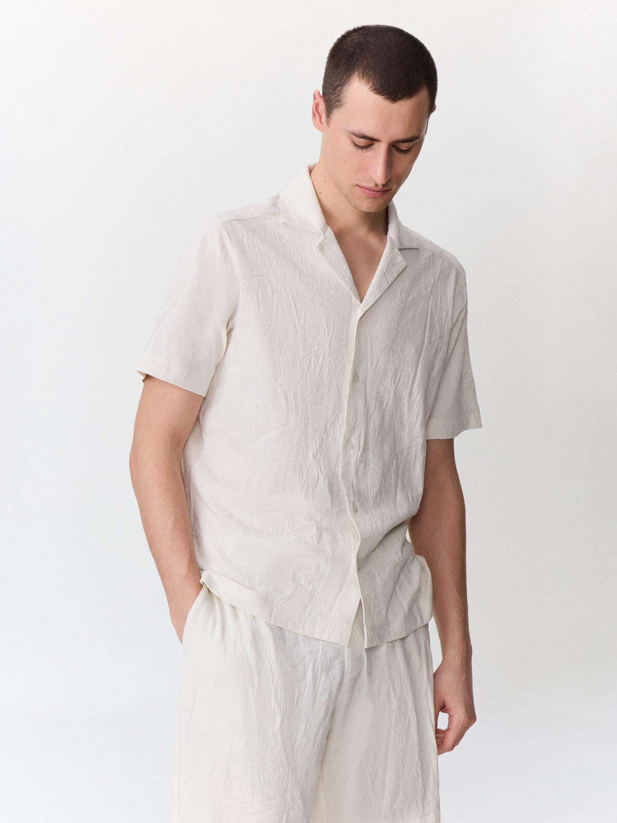 Chemise manches courtes maille beige — vue portée de trois-quarts, main dans la poche