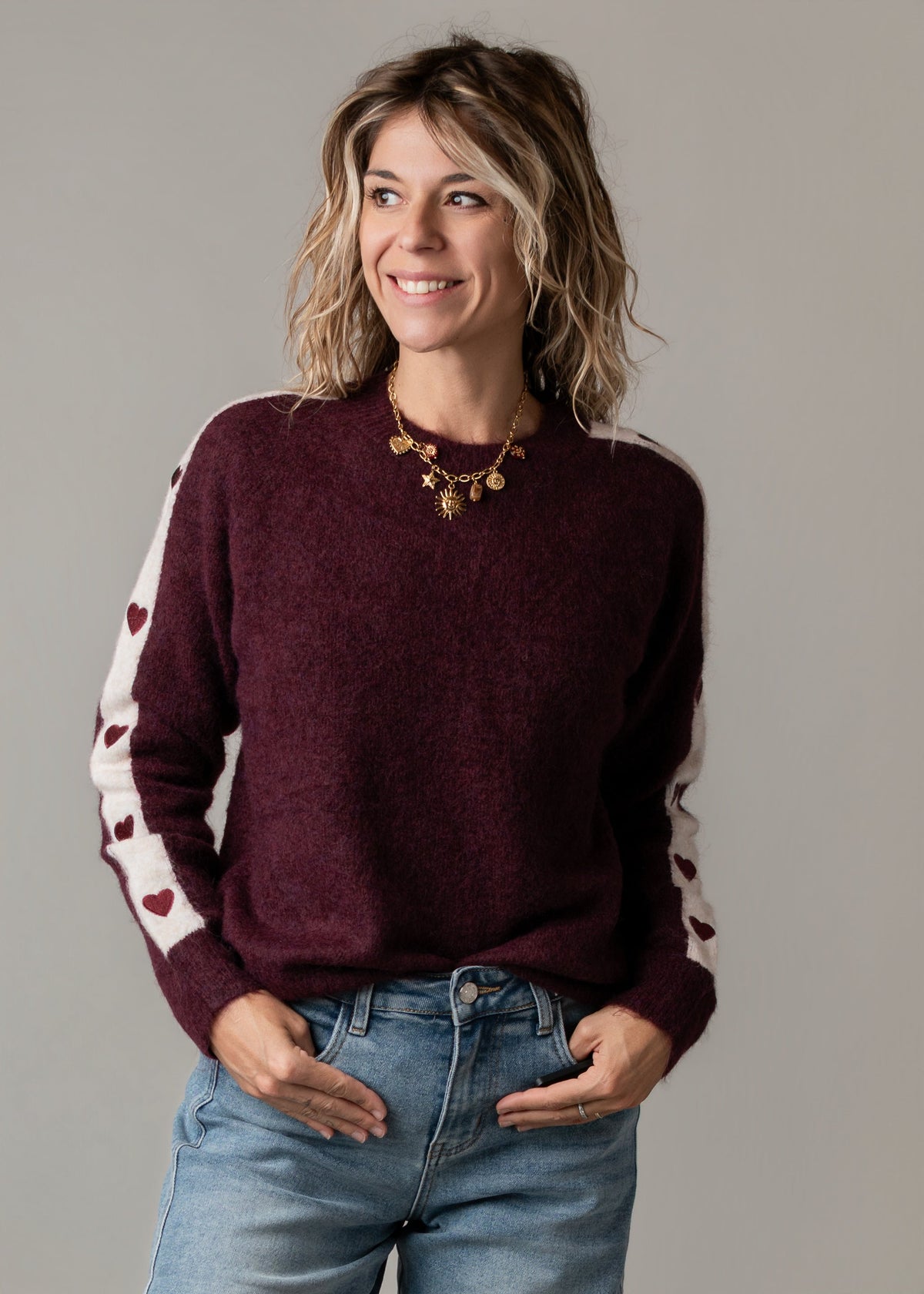 Pull à cœurs brodés porté par une femme, vue rapprochée, cœurs brodés sur les manches, jean