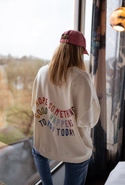 Sweat doux à écritures porté par une femme, vue de dos, inscription colorée, casquette rose, baie vitrée