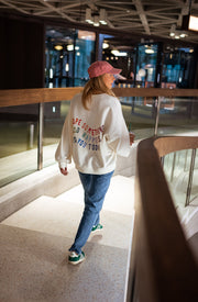 Sweat doux à écritures porté par une femme, en marchant, inscription au dos, passerelle, de loin
