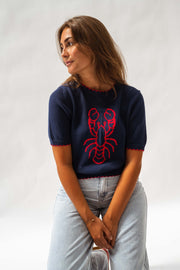 Pull en maille manches courtes porté par une femme, vue de trois-quarts, regard de côté, jean large