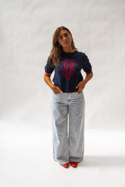 Pull en maille manches courtes porté par une femme, silhouette entière, jean clair, motif homard