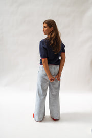 Pull en maille manches courtes porté par une femme, vue de profil, jean large, fond blanc