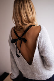 Pull dos ouvert à nœud porté par une femme, vue de dos, dos ouvert, nœud noir