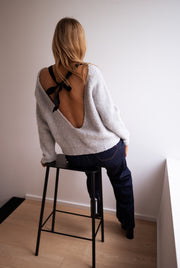Pull dos ouvert à nœud porté par une femme, vue de dos, tabouret, dos ouvert