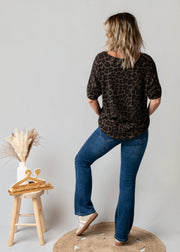 Pull fin col V léopard porté par une femme, vue de dos, tabouret, jean flare