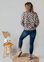 Pull léopard à col V porté par une femme, vue de dos, jean, tabouret