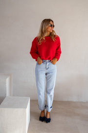 Pull col rond porté par une femme, silhouette entière, jean clair, de loin