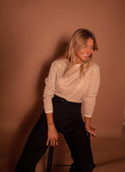 Pull à paillettes col rond porté par une femme, assise, sur un tabouret, regard vers le bas