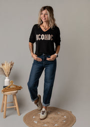 Jean en denim coupe arrondie porté par une femme, silhouette entière, t-shirt à lettres, tabouret
